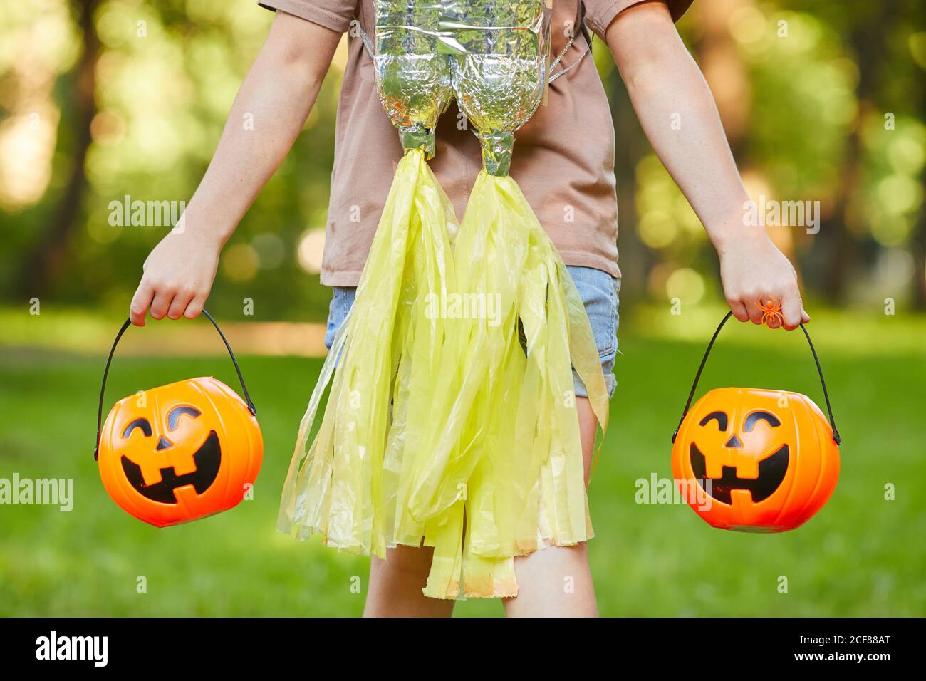 Gros plan des sacs de transport de fille sous forme de citrouilles tout en marchant à l'extérieur Banque D'Images