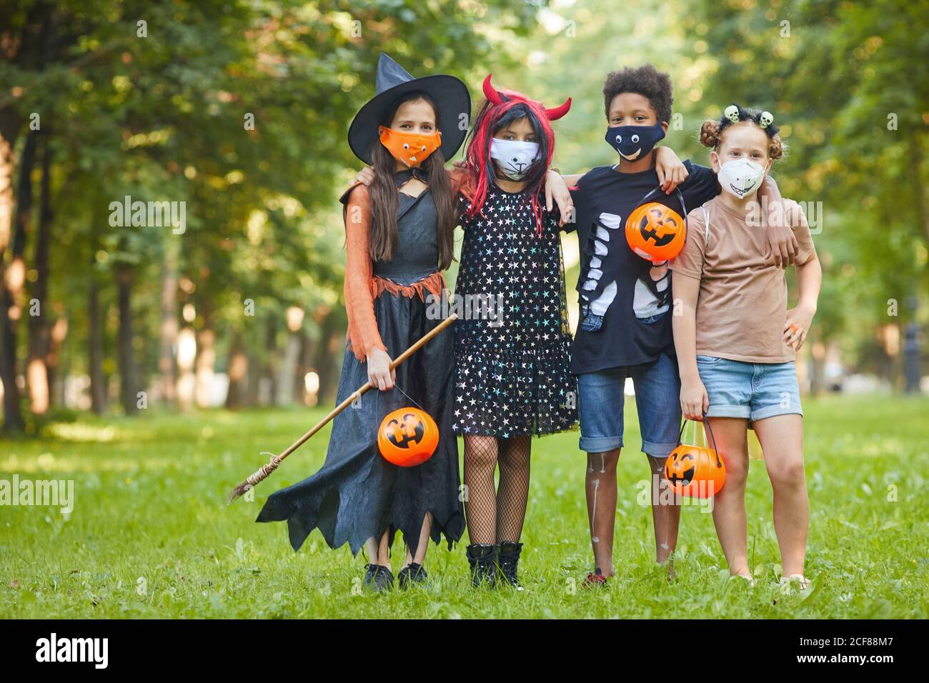 Groupe d'amis en costumes d'Halloween regardant l'appareil photo pendant debout dans le parc, ils célèbrent la fête d'Halloween Banque D'Images