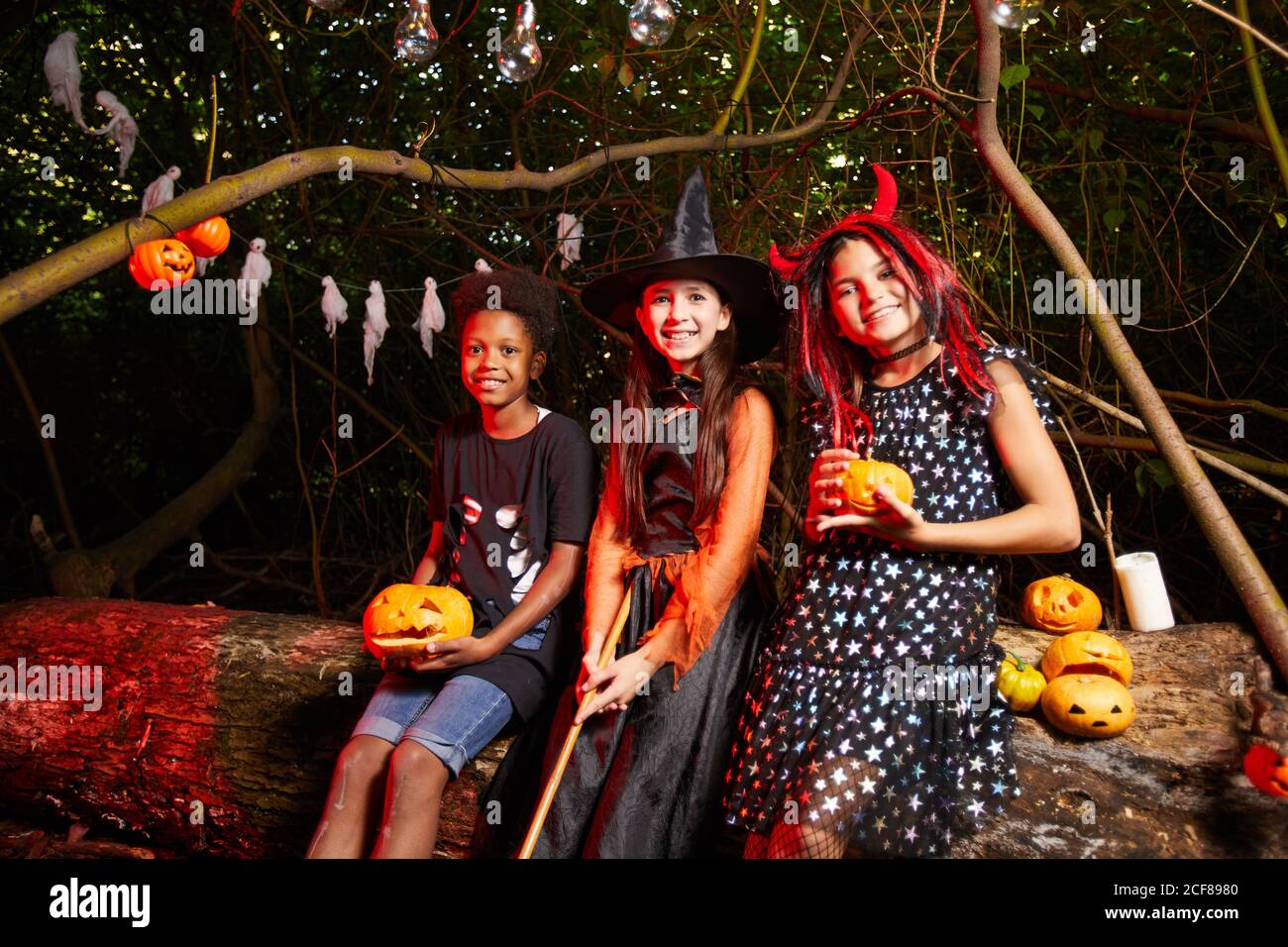 Groupe d'amis en costumes boire du jus de citrouille verres et sourire à la caméra pendant la fête Banque D'Images
