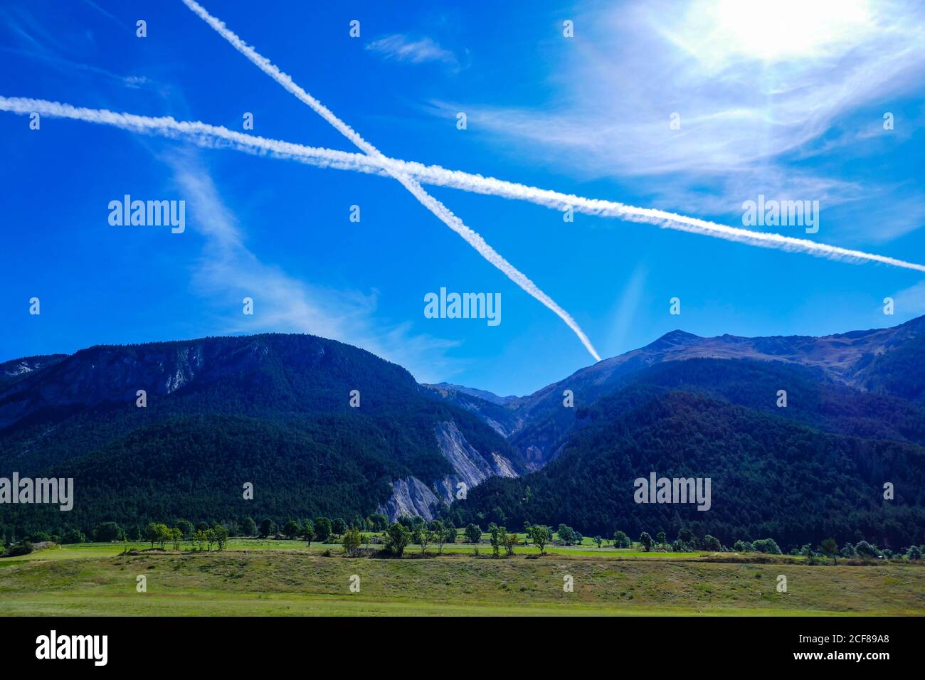 Pistes de vapeur, contrails sous forme de croix, dans le ciel bleu au-dessus des Alpes françaises, Banque D'Images