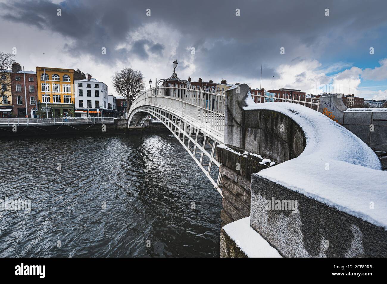 Vue spectaculaire sur le pont Ha ' Penny, recouvert de neige et de nuages denses. Le pont-pont irlandais qui traverse la rivière Liffey offre un sentiment de communauté Banque D'Images