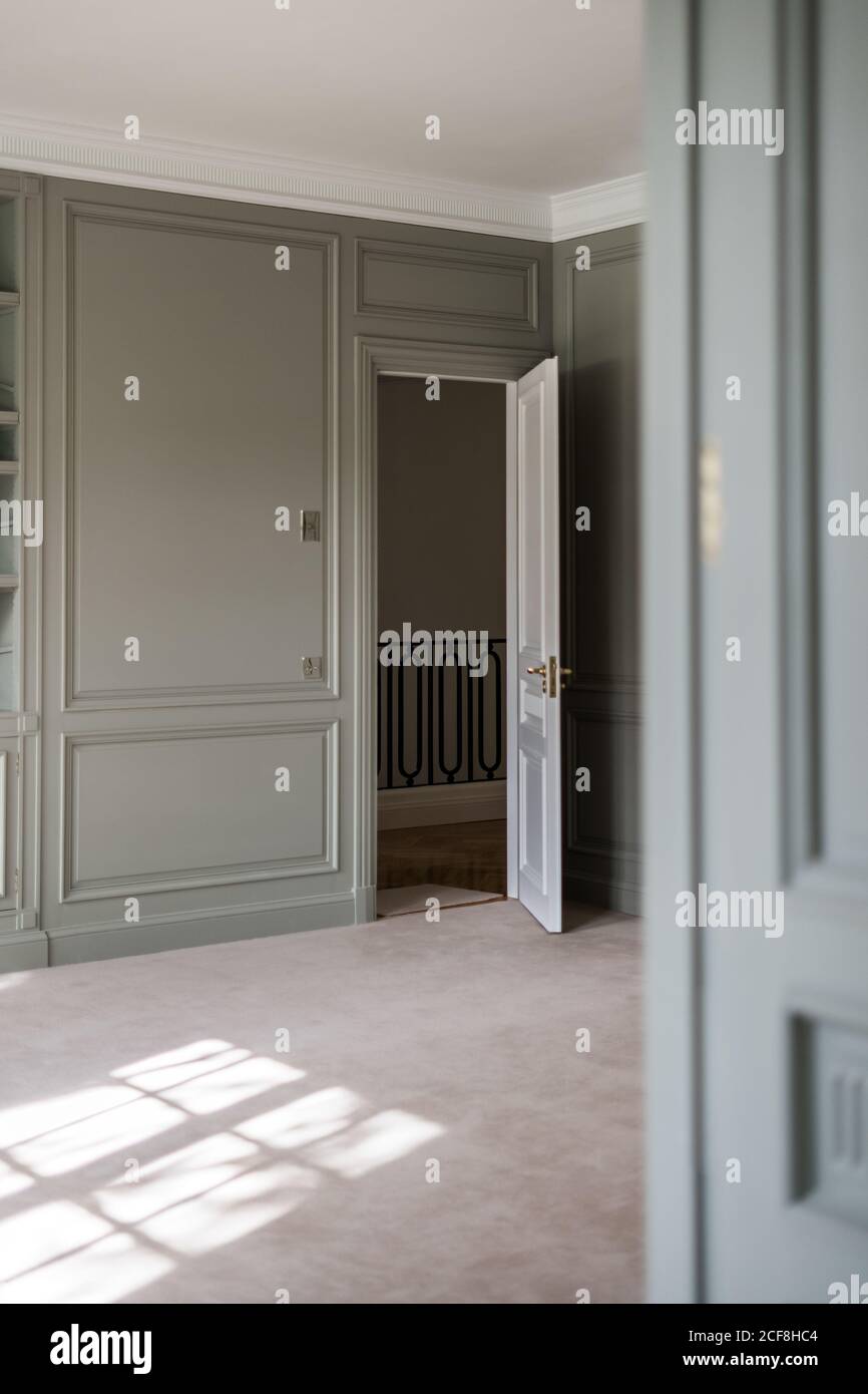 Intérieur de la maison lumineuse avec mur lambrissé et blanc porte ouverte montrant des escaliers de conception minimaliste Banque D'Images