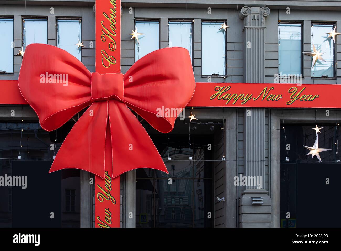 Décoration de Noël sur le bâtiment. Ruban rouge avec inscription Joyeux  Noël et bonne année et un gros noeud. Bâtiment comme un cadeau attaché  satin rouge Photo Stock - Alamy