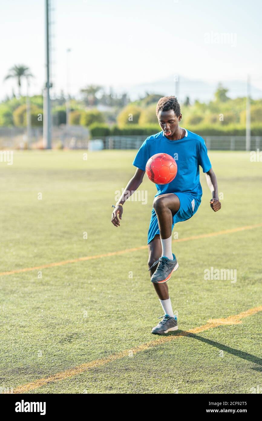 Tout le corps noir adolescent dans bleu sportswear jugling rouge balle sur  le genou pendant l'entraînement sur le terrain de football Photo Stock -  Alamy