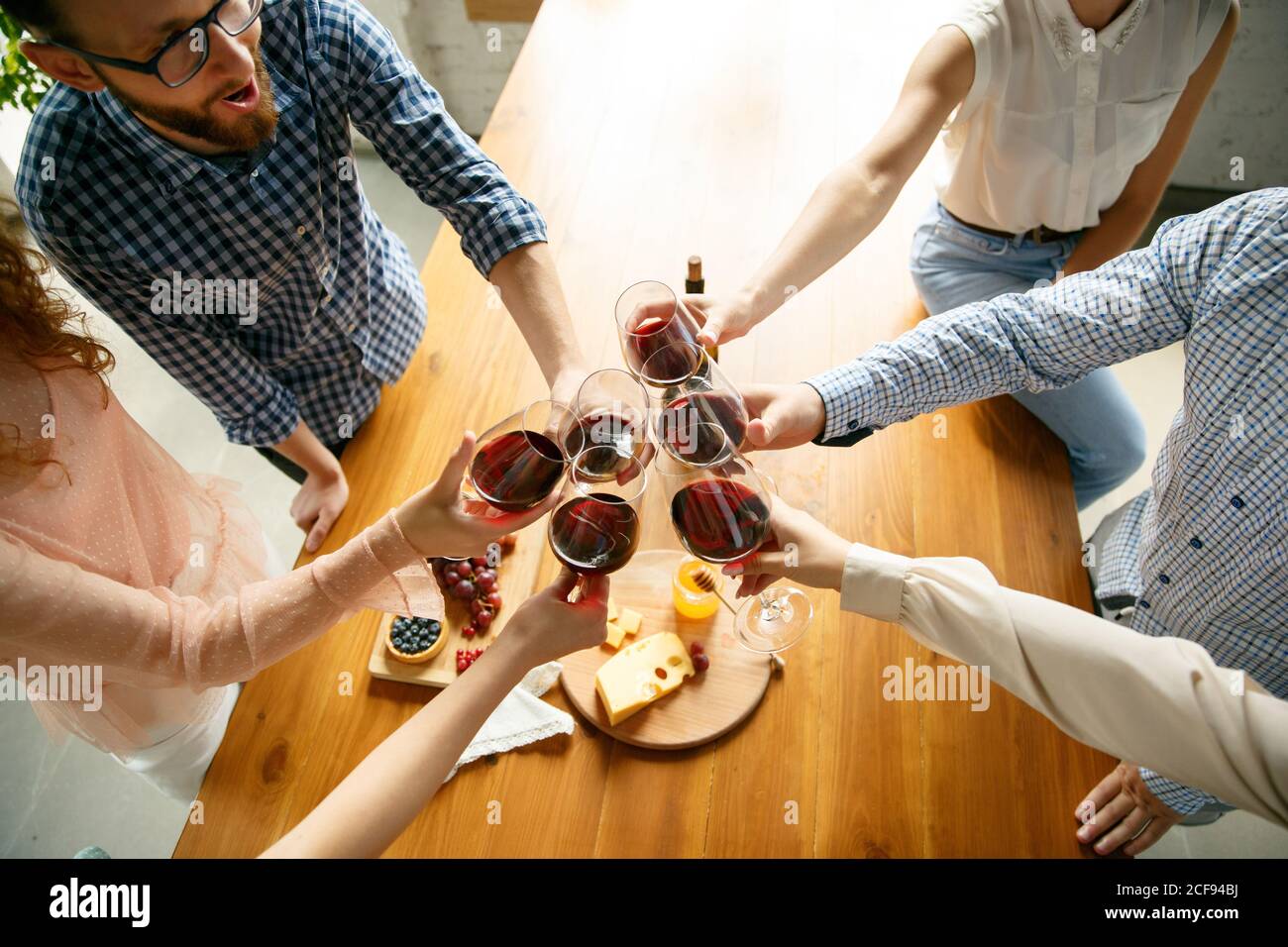 Bonnes vibrations. Les gens clinking verres avec du vin ou du champagne. Des amis heureux et joyeux célèbrent les vacances, la réunion. Gros plan sur des amis souriants, le style de vie. Faites la fête à la maison ou au restaurant, au café. Banque D'Images