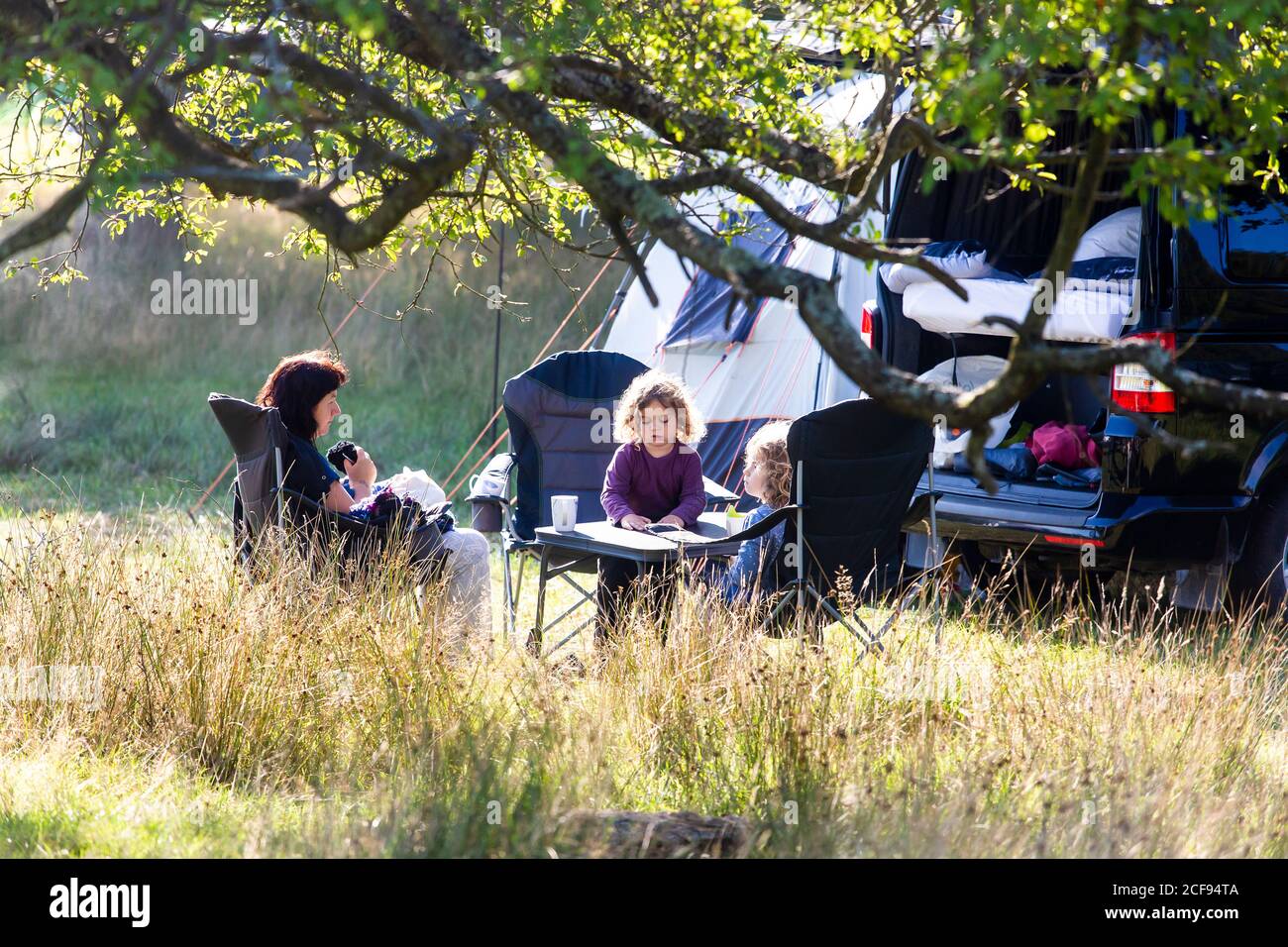 Les campeurs en famille qui profitent du soleil le matin ne sont pas un Festival socialement distancé événement dans le parc de Pippingford - camping avec une vibe de festival Banque D'Images