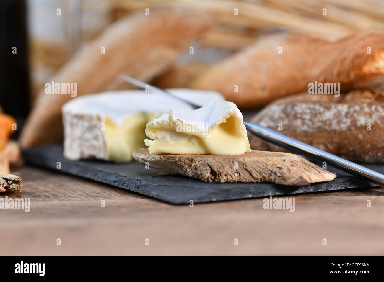 Délicieux fromages blancs et pain frais croustillant avec des morceaux de bois sur table rustique Banque D'Images