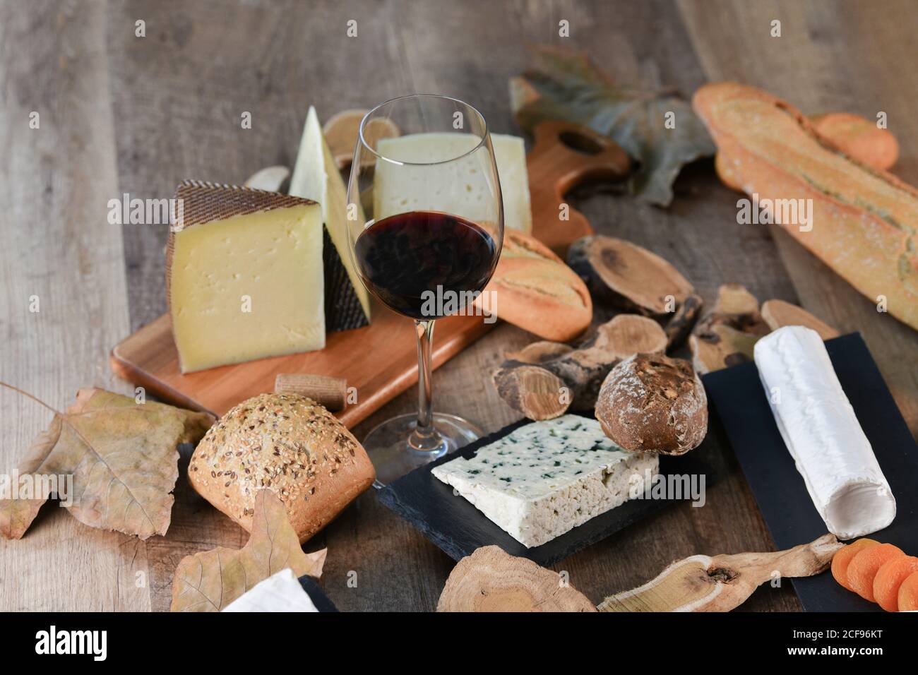 De ci-dessus savoureuses tranches maison de fromage blanc et frais pain croustillant avec bouteille et verre de vin rouge table rustique en bois Banque D'Images
