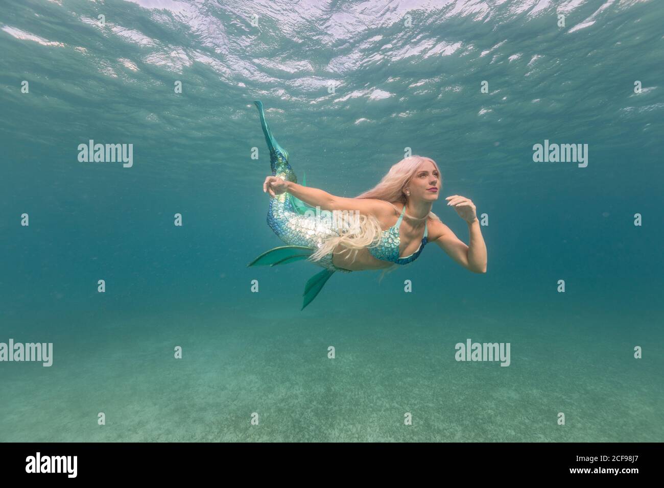 Belle petite sirène insouciante avec queue de poisson bleue nager sous l'eau mer profonde et lumineuse Banque D'Images