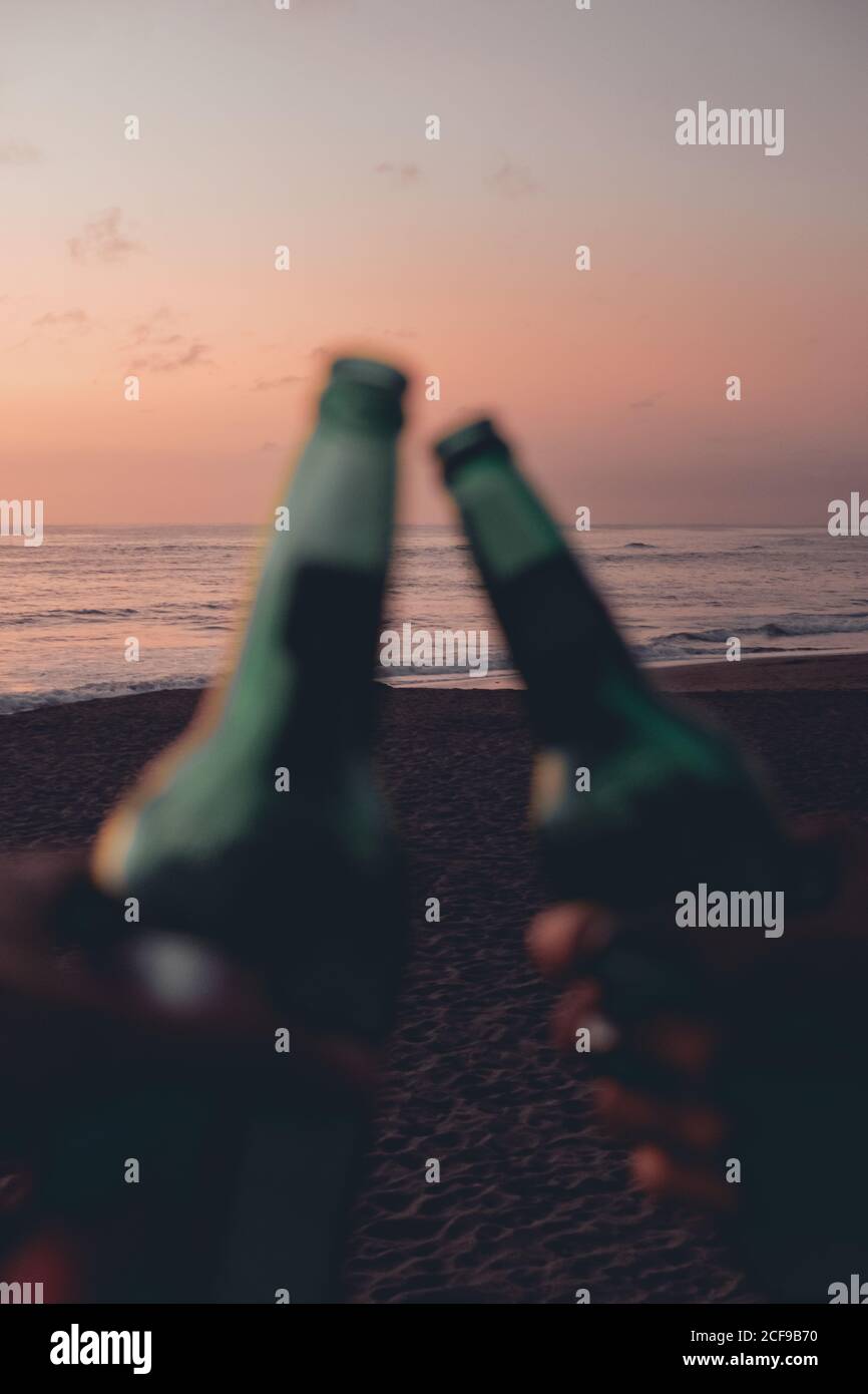 Des amis qui toaster avec de la bière sur la plage au coucher du soleil Banque D'Images