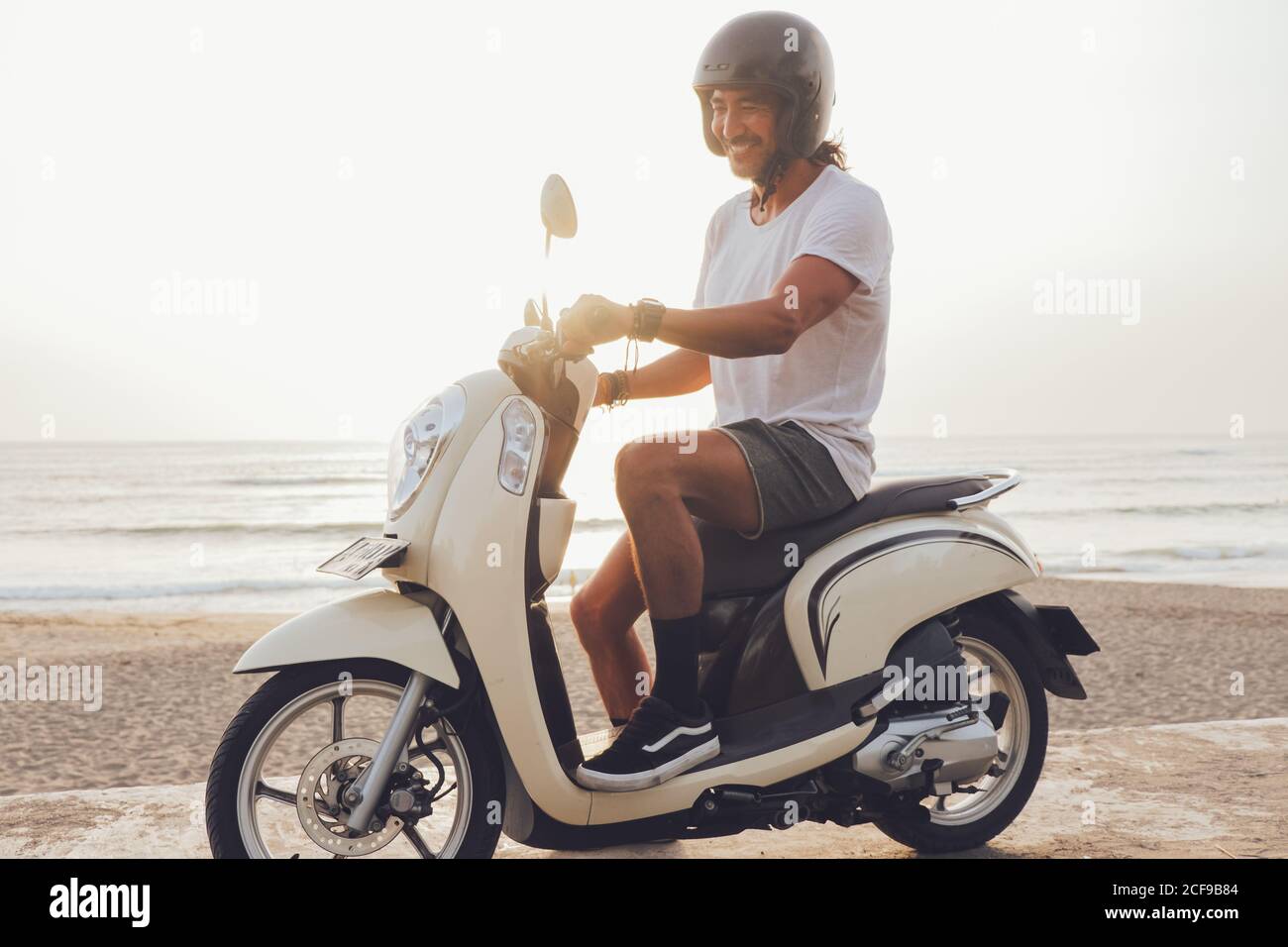 Motard joyeux sur une plage de sable Banque D'Images