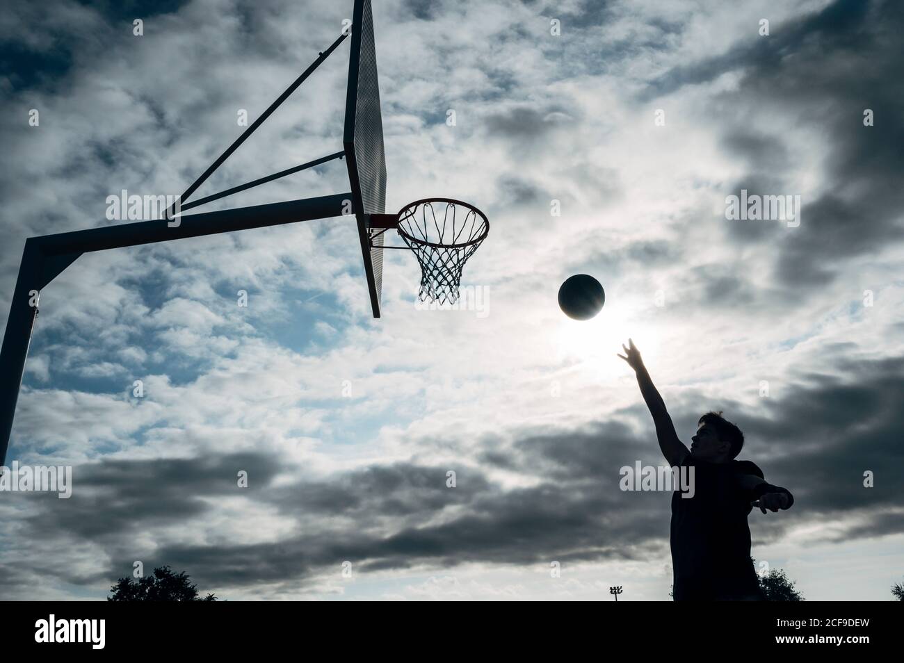 Jeune homme jouant sur un terrain de basket-ball extérieur. Banque D'Images