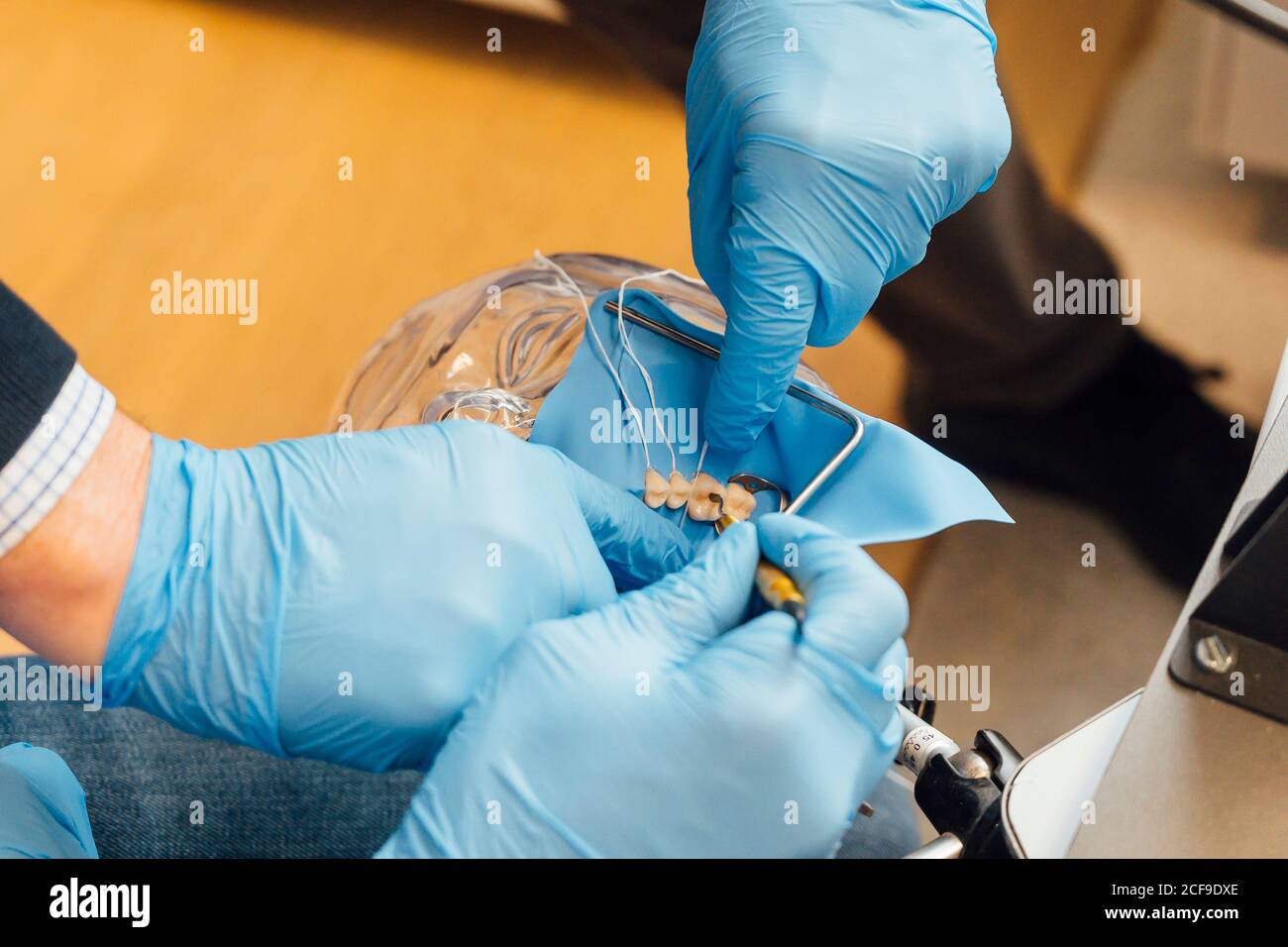 Du dessus de l'enseignant de dentisterie de récolte aidant l'étudiant dans la performance tout en travaillant avec un simulateur dentaire dans un laboratoire moderne Banque D'Images