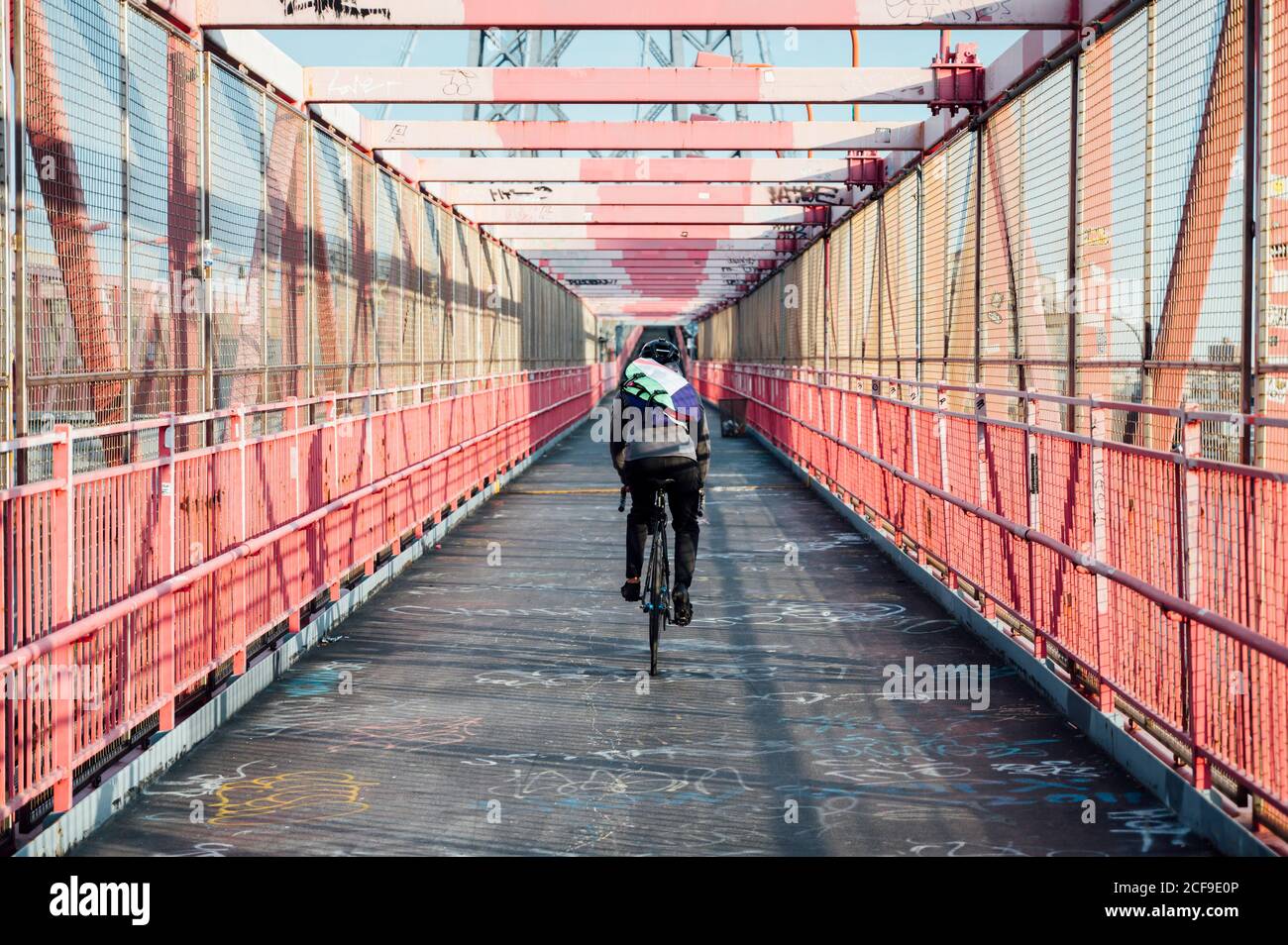 Vue arrière d'un cycliste anonyme avec casque à vélo Structure de pont en  métal rouge dans la ville de New York Photo Stock - Alamy