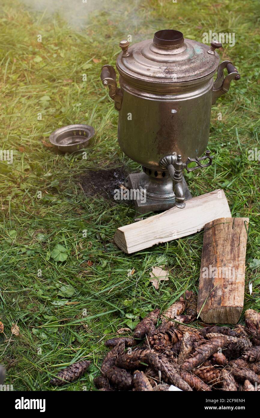 Chauffer le samovar avec des cônes pour faire du thé. Le samovar repose sur l'herbe. Fumée du tuyau Banque D'Images