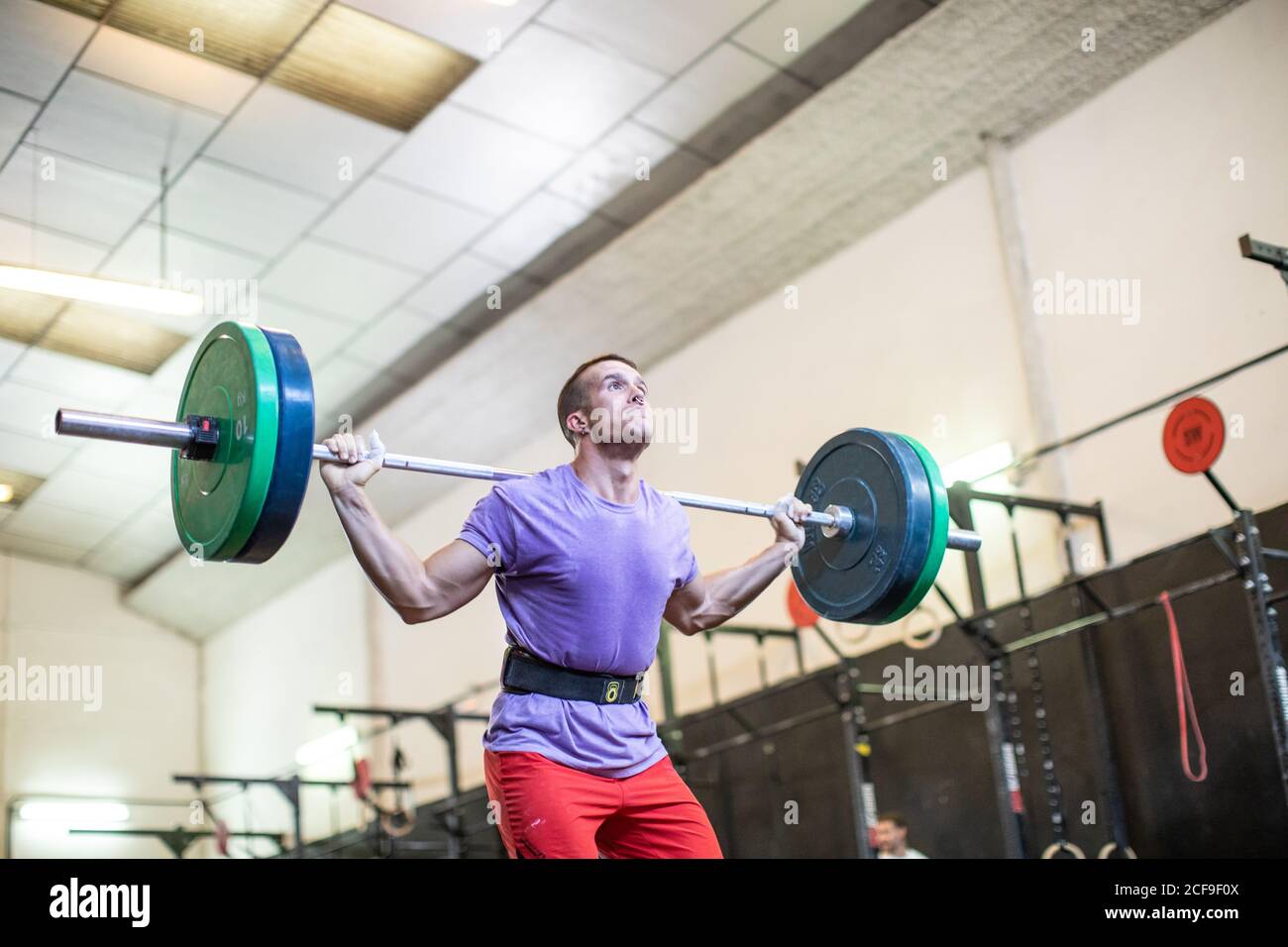 Un homme musclé qui lève la barbell dans une salle de sport moderne Banque D'Images