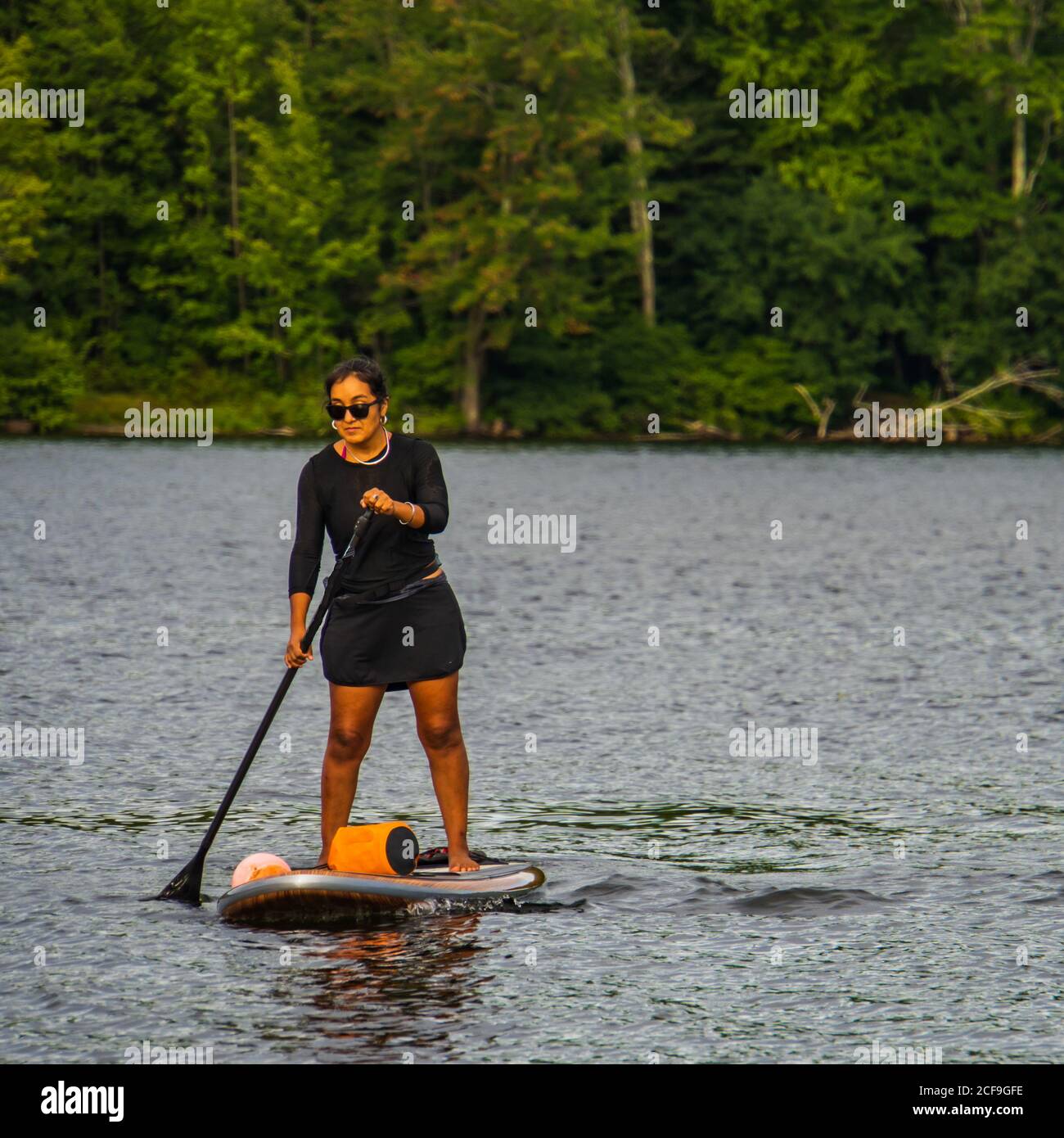 une jeune femme appréciant la journée d'été sur un lac avec une planche à palettes Banque D'Images