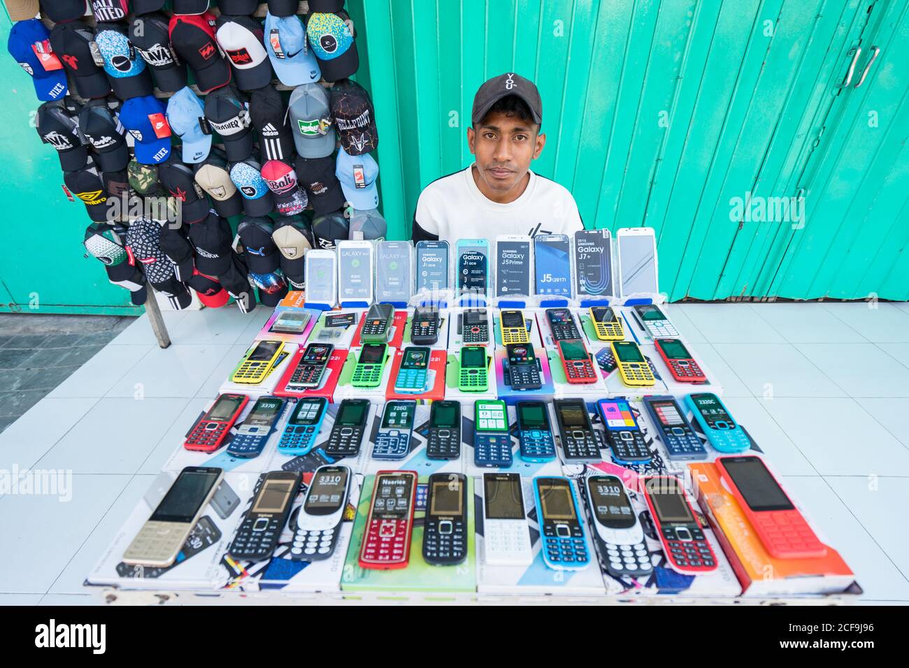 Dili, Timor oriental - 09 AOÛT 2018 : jeune vendeur asiatique de sexe masculin vendant des appareils électroniques et des casquettes dans la rue de la ville Banque D'Images