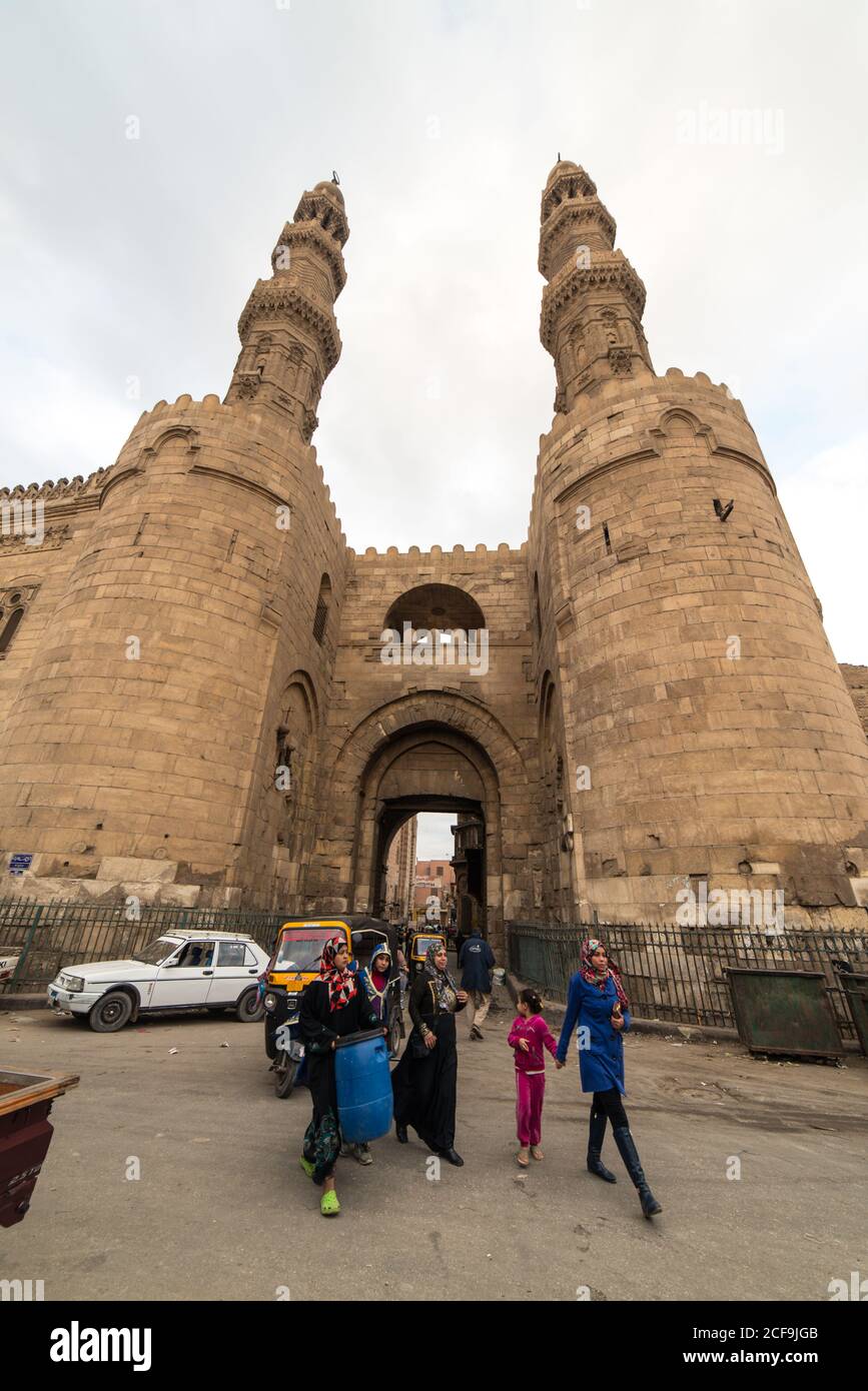 Le Caire, Egypte - 14 décembre 2019 : personnes marchant dans la vieille rue contre un château en pierre ancien avec arche et tours Banque D'Images