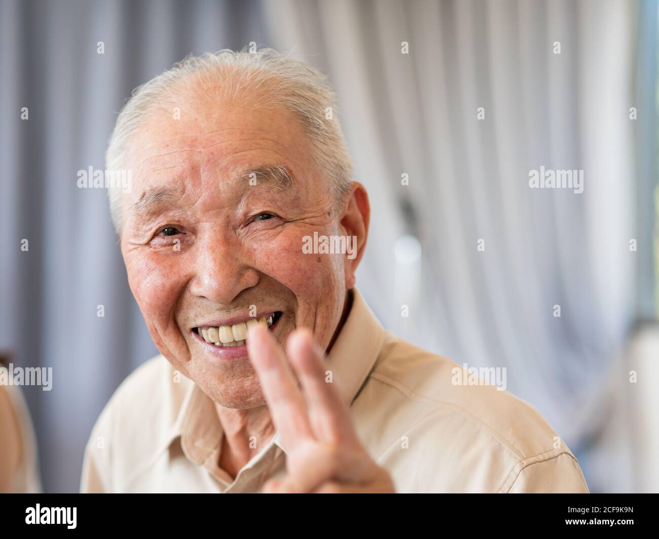 Un homme âgé souriant et montrant un signe de paix Banque D'Images