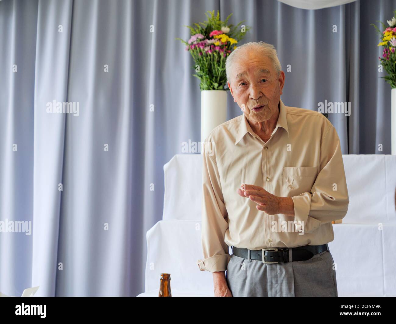 Un homme asiatique âgé prononce un discours lors d'un événement familial Banque D'Images