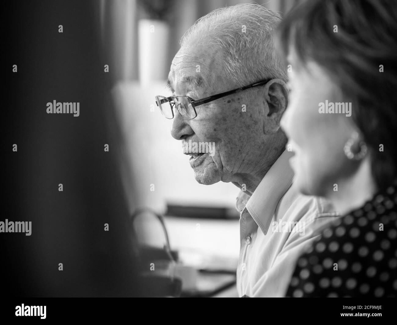 Un très vieux homme asiatique parlant heureusement pendant qu'il est entouré sa famille Banque D'Images