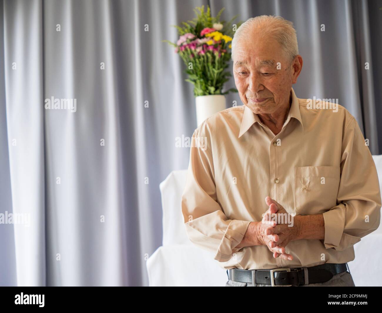 Un homme asiatique âgé prononce un discours lors d'un événement familial Banque D'Images