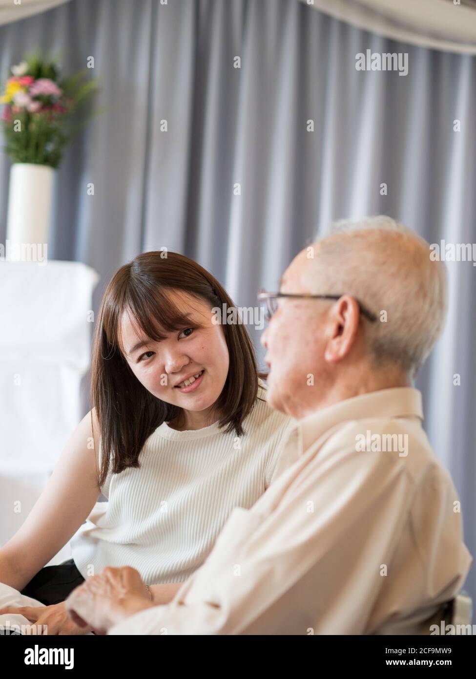 Un vieil homme parle heureusement avec sa petite-fille adulte Banque D'Images