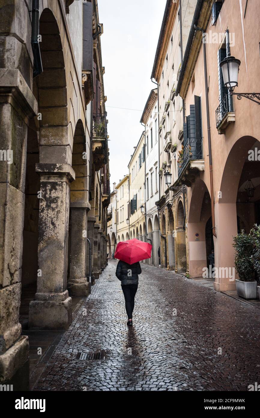 Vue arrière d'un voyageur méconnaissable avec des vêtements chauds Parapluie rouge avec de vieux bâtiments sur un fond flou à Padoue En Italie Banque D'Images