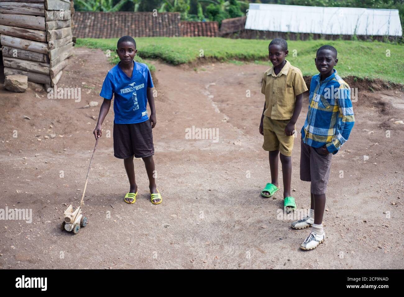 Ruanda, Afrique - 14 décembre 2019: Groupe d'adolescents africains souriants en tenue décontractée debout ensemble sur la cour du village jouant ensemble et regardant la caméra Banque D'Images