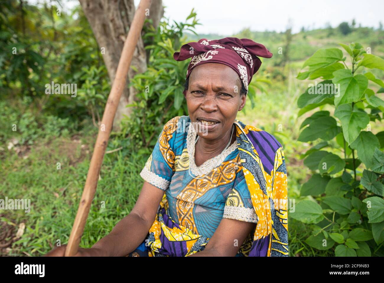 Ruanda, Afrique - 14 décembre 2019: Afro-américain frognant vieille dame en robe colorée assis dans la nature regardant la caméra Banque D'Images