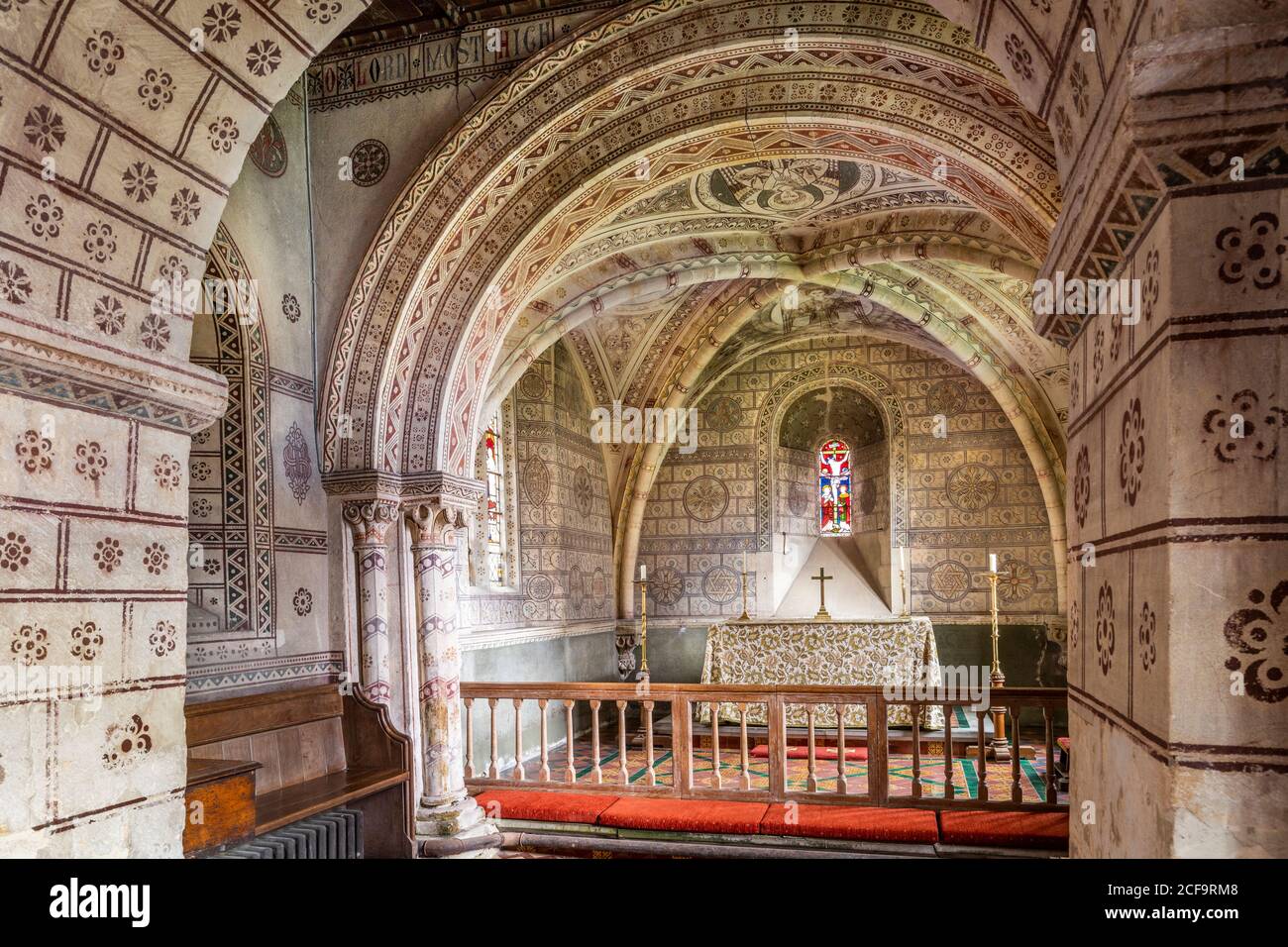 L'église normande de St George dans le village de Hampnet, dans les Cotswolds, montrant le chœur du XIIe siècle décoré dans les années 1870 par le vicaire à l'époque. Banque D'Images