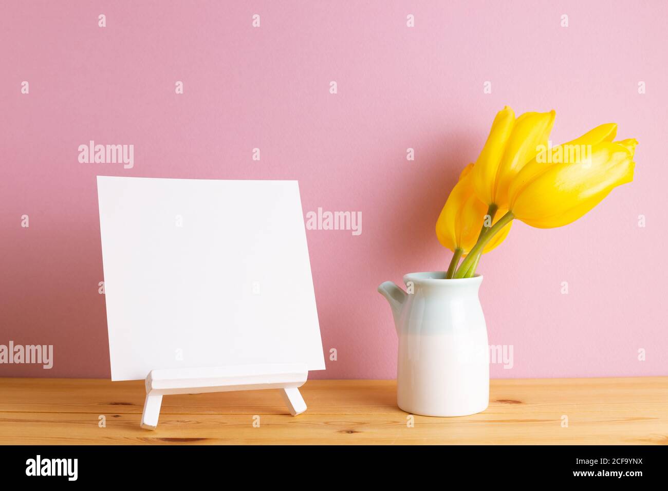 Toile vierge sur chevalet avec fleurs de tulipe jaunes sur bois table avec fond rose Banque D'Images
