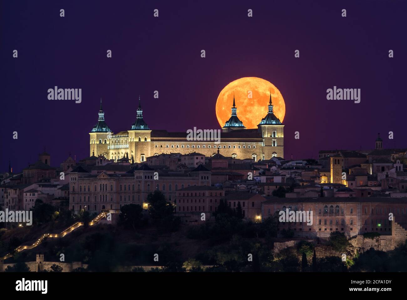 Magnifique paysage d'un ancien palais illuminé construit au-dessus de la ville Nuit colorée avec pleine lune rouge à Tolède Banque D'Images