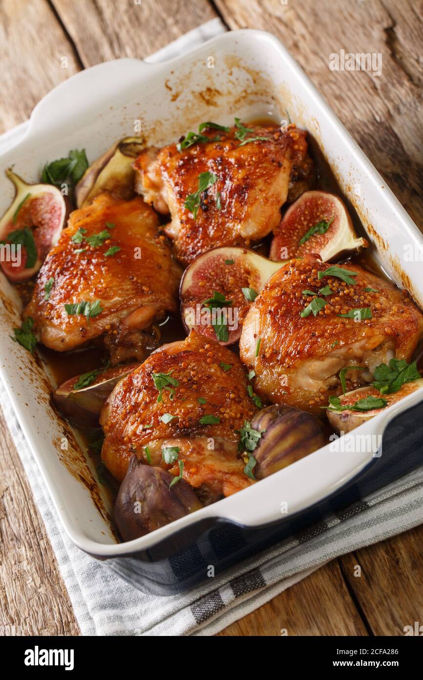 Délicieux cuisses de poulet balsamique cuites au four avec figues et herbes en gros plan dans un plat de cuisson sur la table. Vertical Banque D'Images