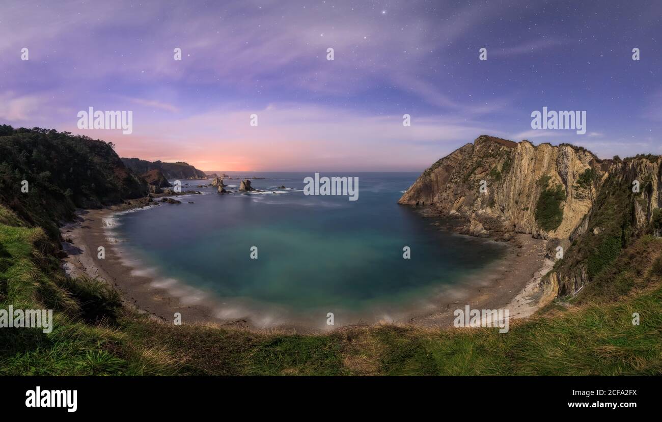 Plage solitaire de lagon calme parmi les falaises rugueuses avec coloré ciel du soir sur fond Banque D'Images