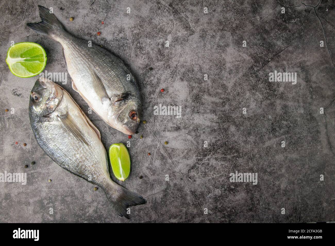 Poisson dorado cru avec des ingrédients pour faire sur un fond blanc d'ardoise, de pierre ou de béton. Vue de dessus avec espace de copie Banque D'Images