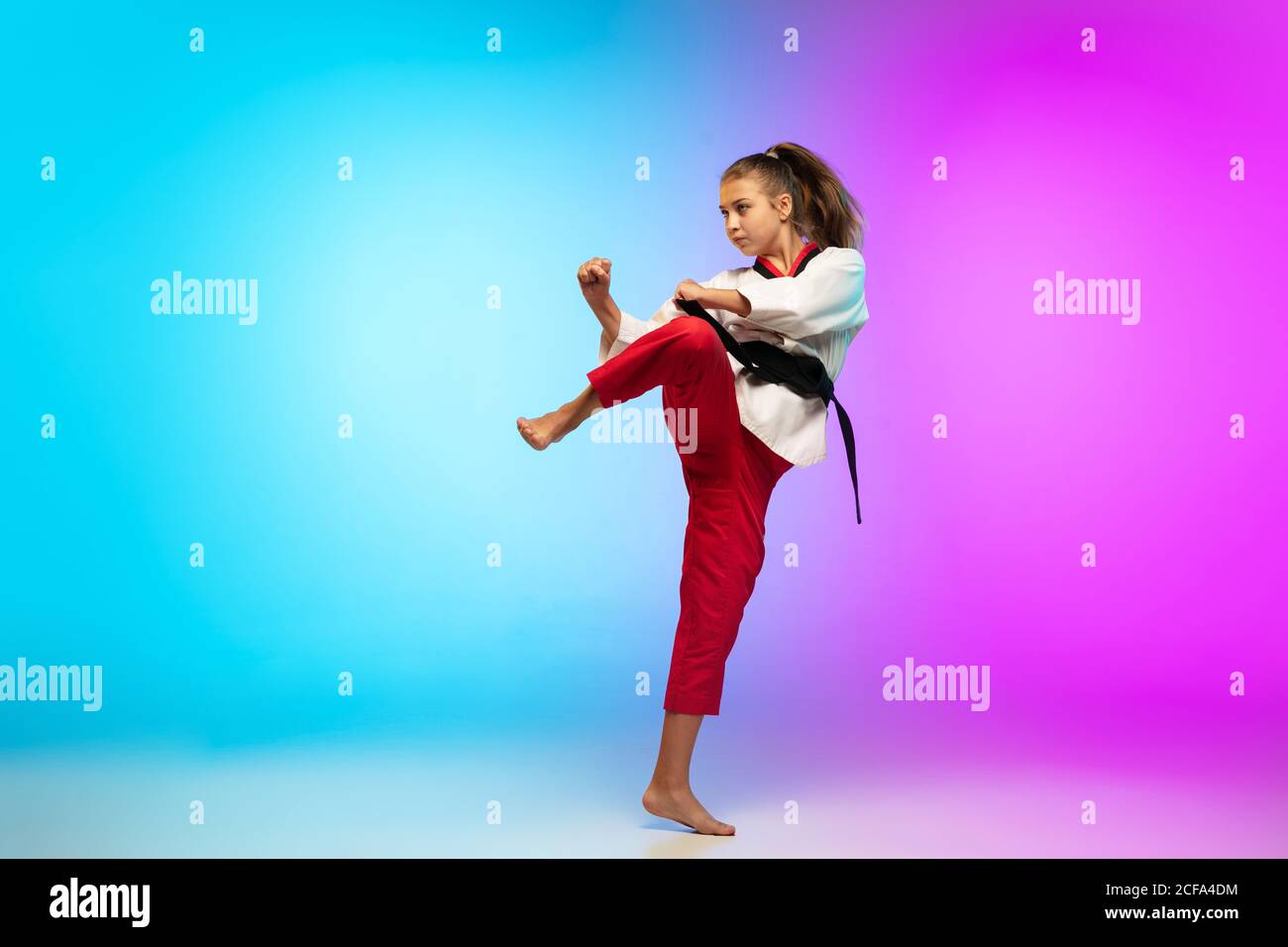 Frapper. Karate, taekwondo fille avec ceinture noire isolée sur fond  dégradé dans la lumière de néon. Petit modèle caucasien, entraînement  sportif pour enfants en mouvement et en action. Sport, mouvement, concept  d'enfance
