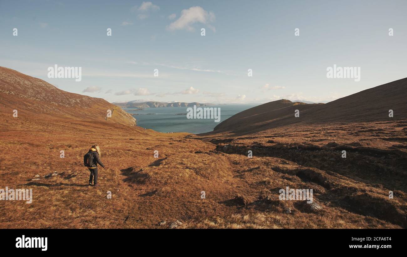 Vue arrière d'une femme méconnaissable marchant sur un paysage merveilleux Et la mer en se tenant sur la falaise en Irlande en regardant loin Banque D'Images