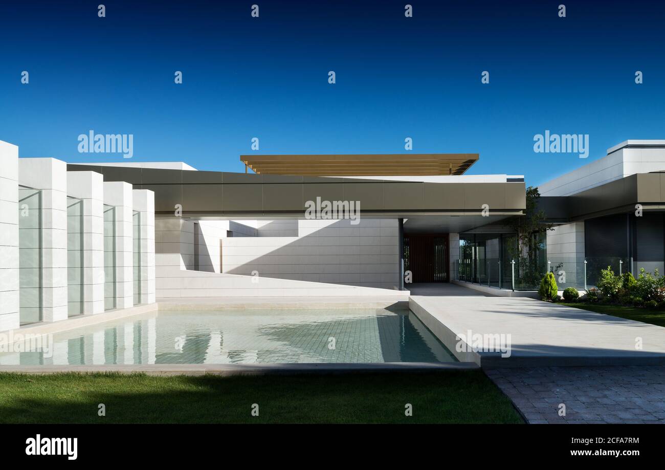 Extérieur d'une maison résidentielle contemporaine de style minimaliste et piscine avec de l'eau claire dans l'arrière-cour le jour ensoleillé Banque D'Images