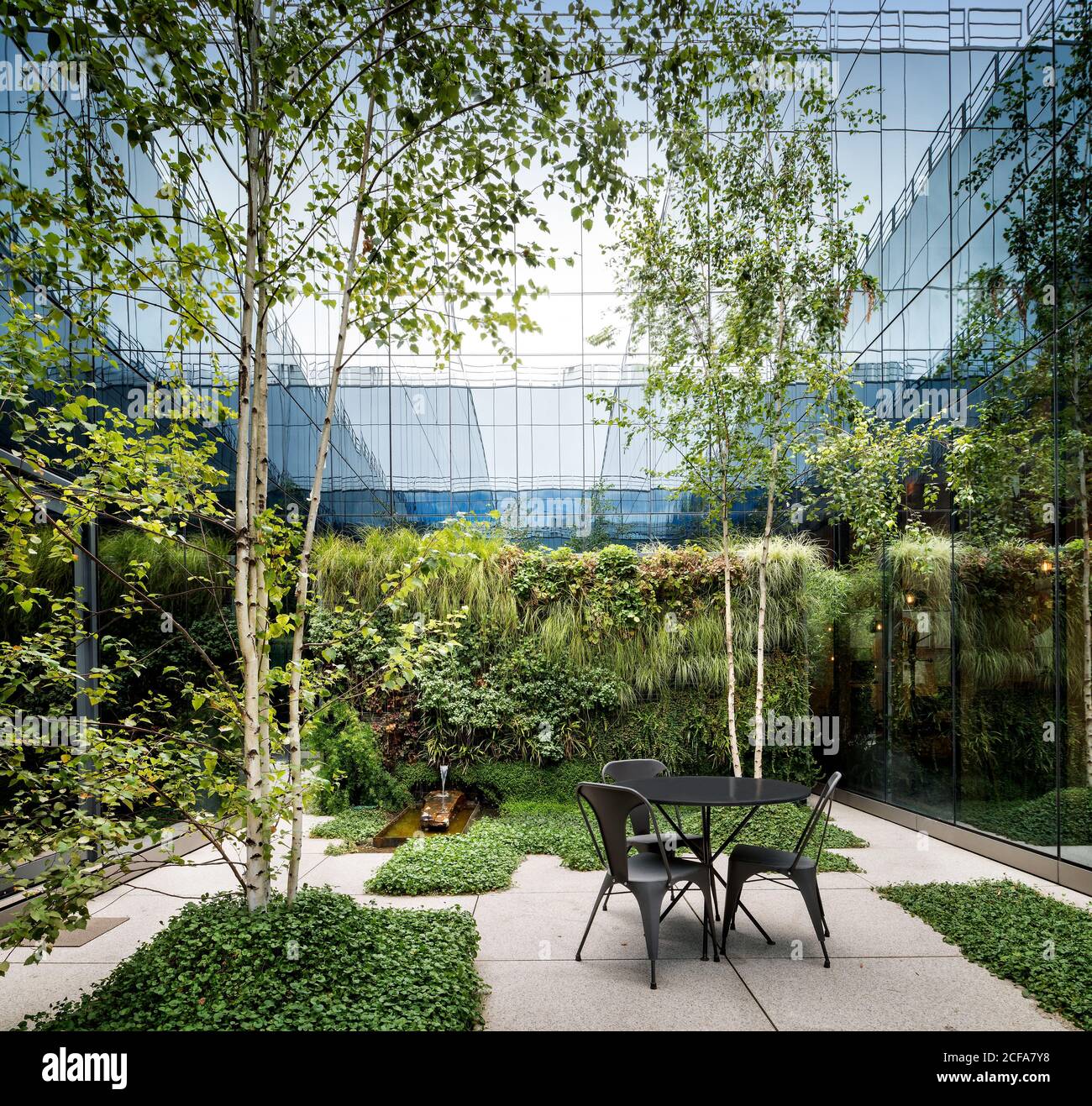 Terrasse confortable avec arbres et salle à manger entourée de verre murs d'un bâtiment moderne Banque D'Images