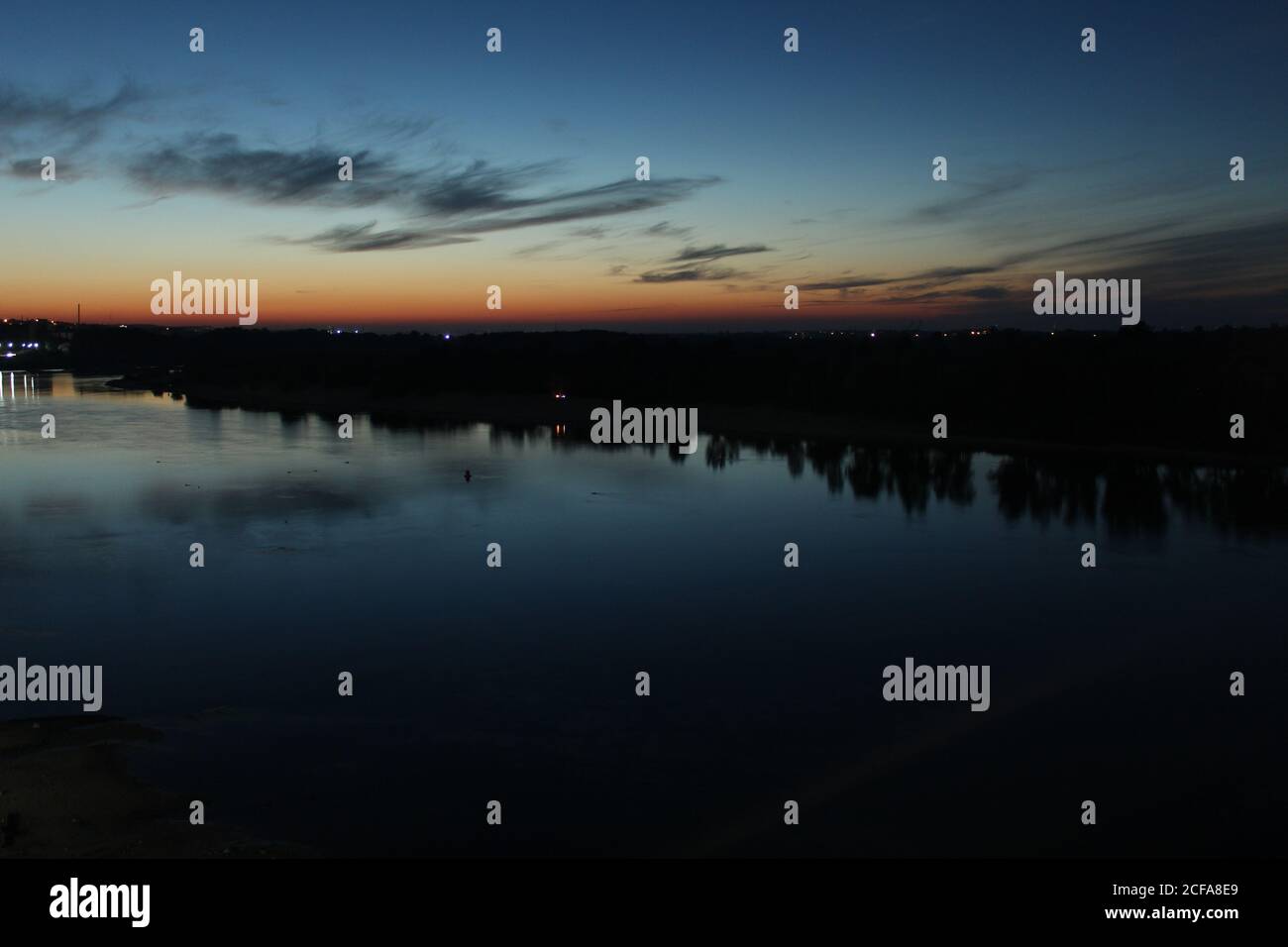 Coucher de soleil sur la rivière bleu et rouge ciel étoiles et forêt d'arbres reflétée sur l'eau Banque D'Images