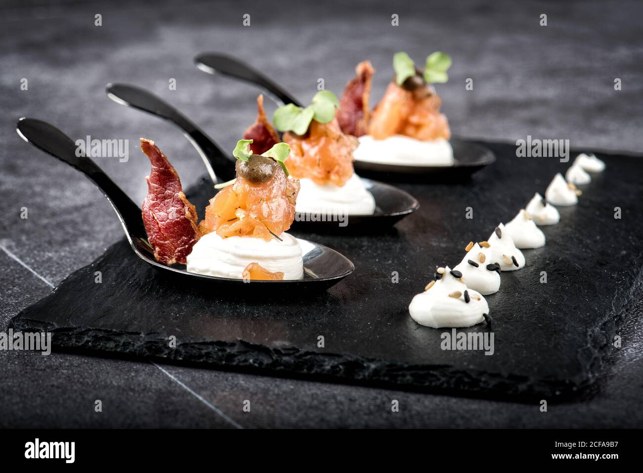 Des portions de saumon fumé et de tranches de viande appétissant sont placées sur le dessus plateau en ardoise avec fromage à la crème dans un restaurant de luxe Banque D'Images