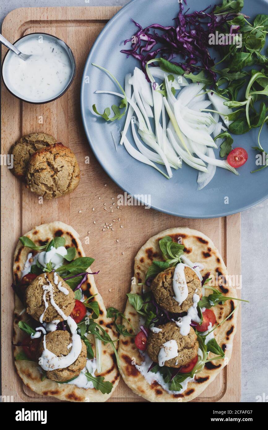 Par dessus la composition de la nourriture falafel et légumes frais sur du pain avec de la salade sur la planche à découper Banque D'Images