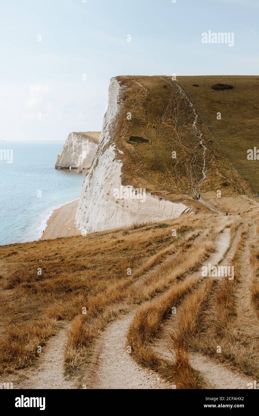 Vue pittoresque sur la mer bleue et les rochers en pierre blanche Avec la voie sur l'herbe près de la porte Durdle le jour Banque D'Images