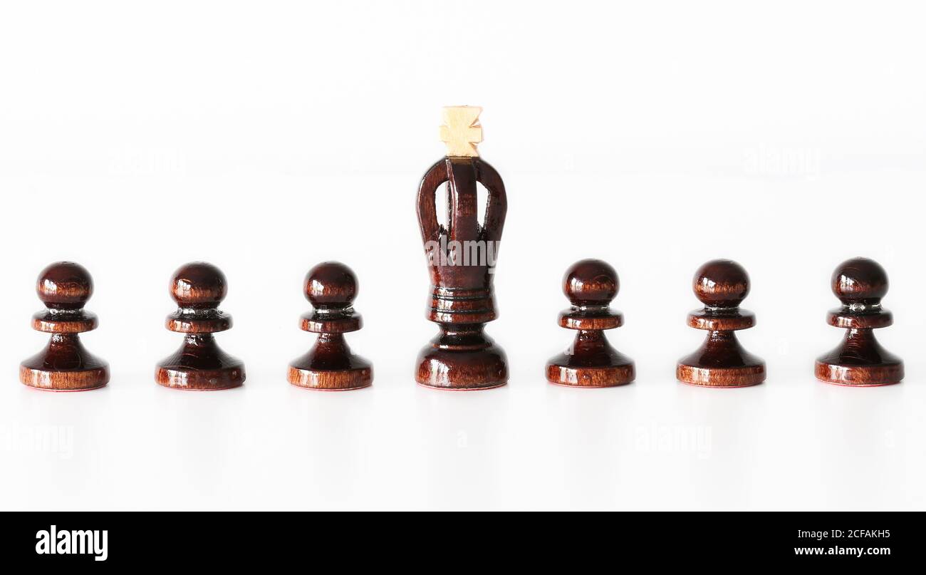 Rangée de pièces d'échecs de pion noir avec roi dans le milieu sur fond blanc - démarquez-vous de la foule concept Banque D'Images