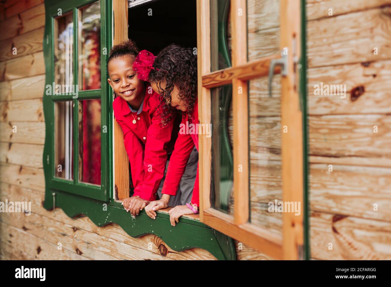 Jolis petits frères et sœurs noirs souriant par une fenêtre ouverte en bois cabine Banque D'Images