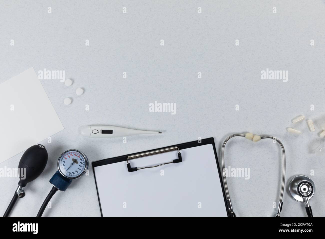 Vue d'une composition avec des dispositifs médicaux, des pilules et un dossier avec une feuille de papier sur le blanc Banque D'Images