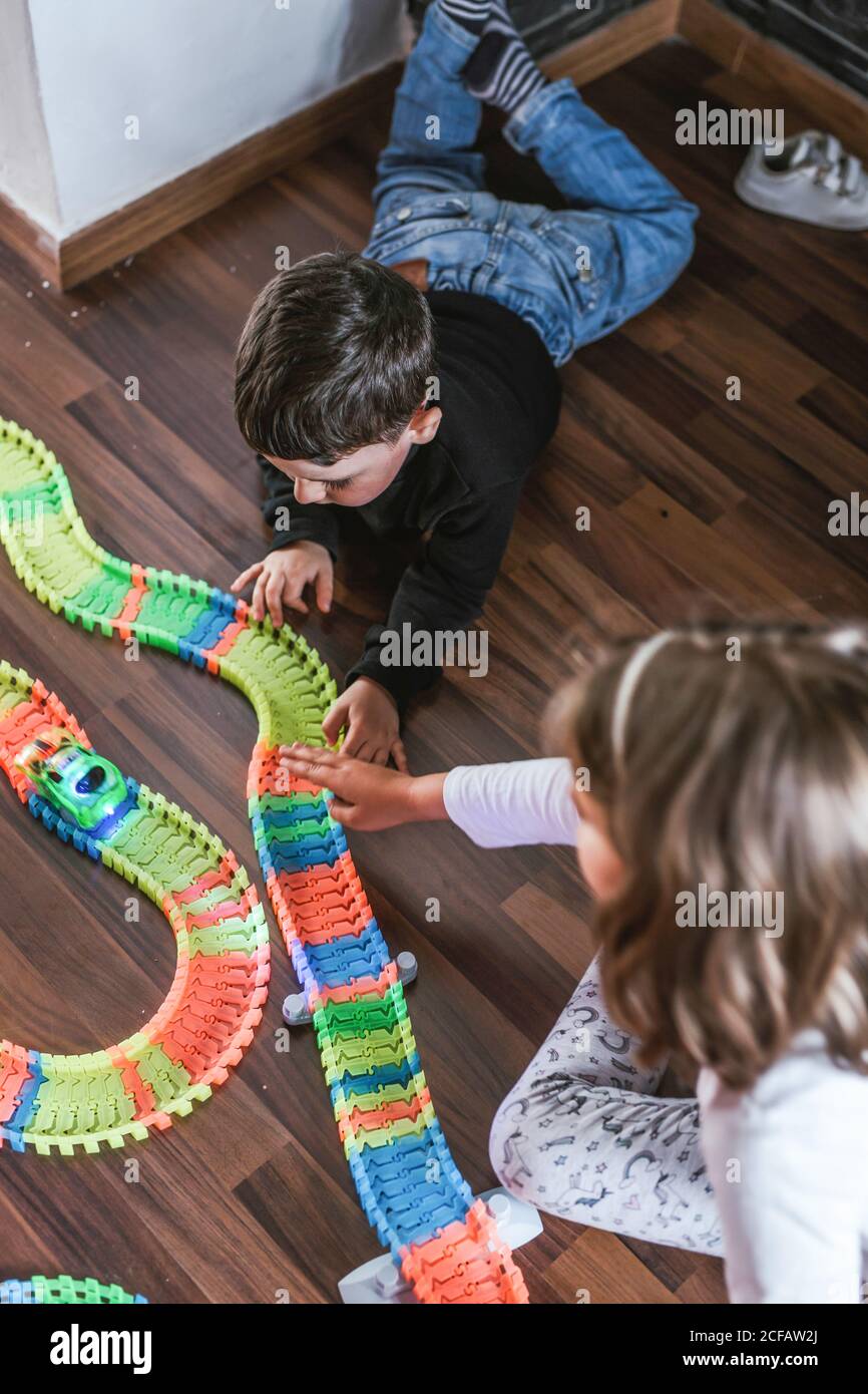 garçon et fille jouant avec les voitures et la route de jouet sur le parquet à la maison ensemble Banque D'Images