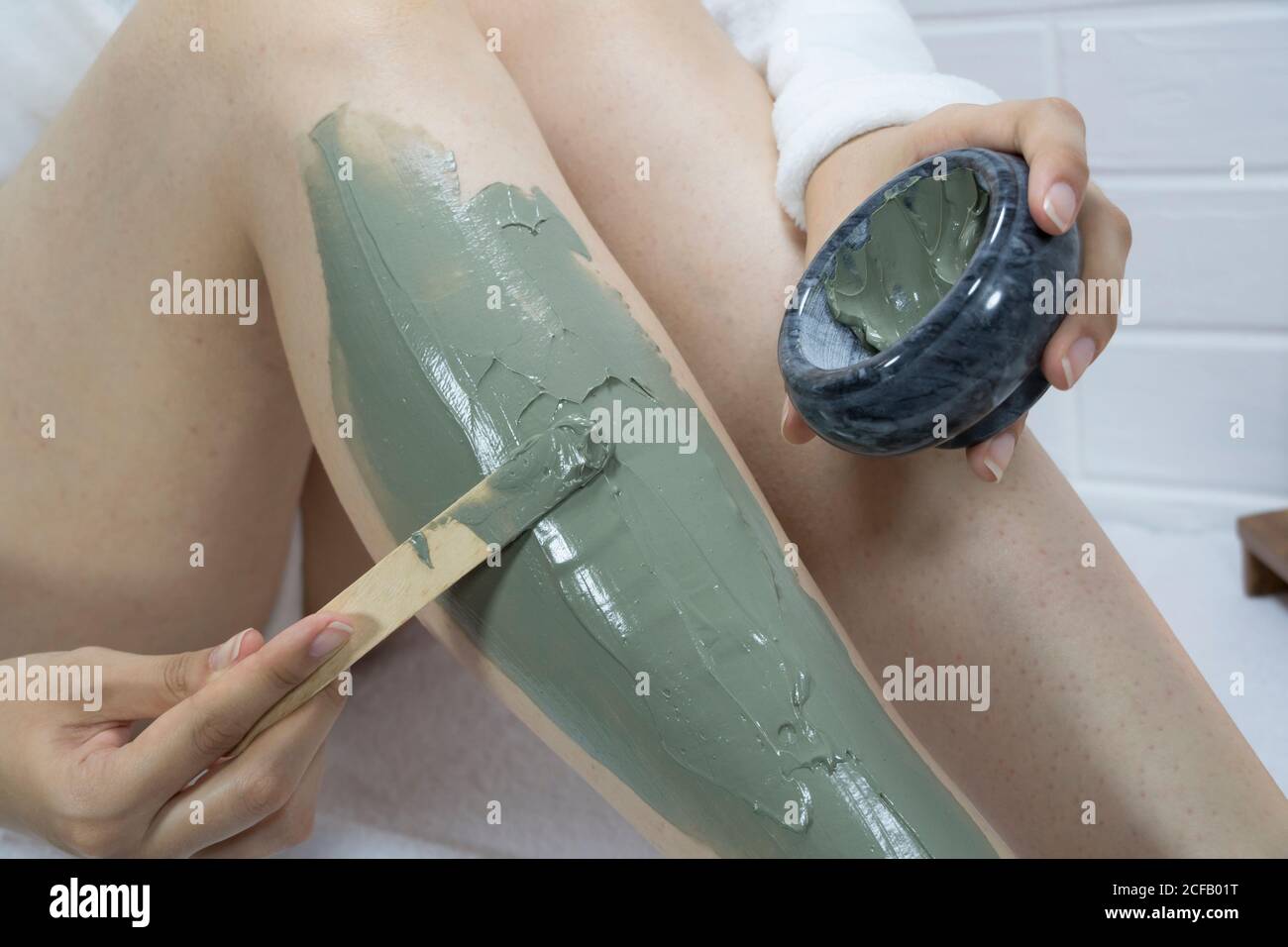 SPA, hydratant, traitement. Une femme applique un masque en argile avec une  spatule sur la peau de ses jambes. Irritation après épilation, rasage. Soins  de la peau à domicile Photo Stock -